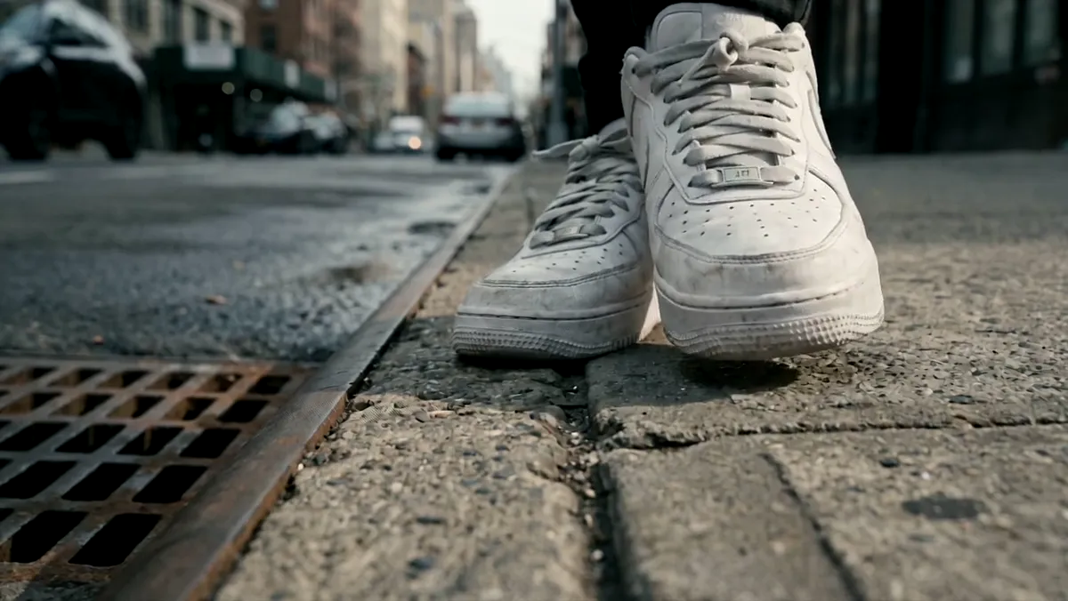 White sneakers stepping off a curb
